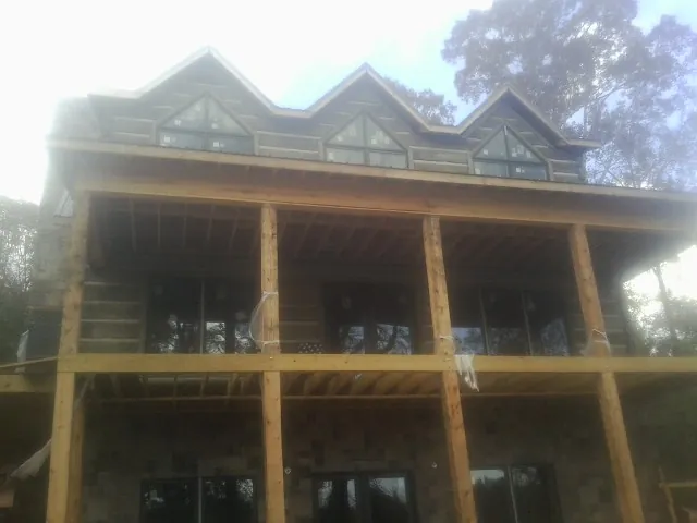 Dormers and porch framing on a large log home under construction — Roof Coating work by our crew in Mannsville