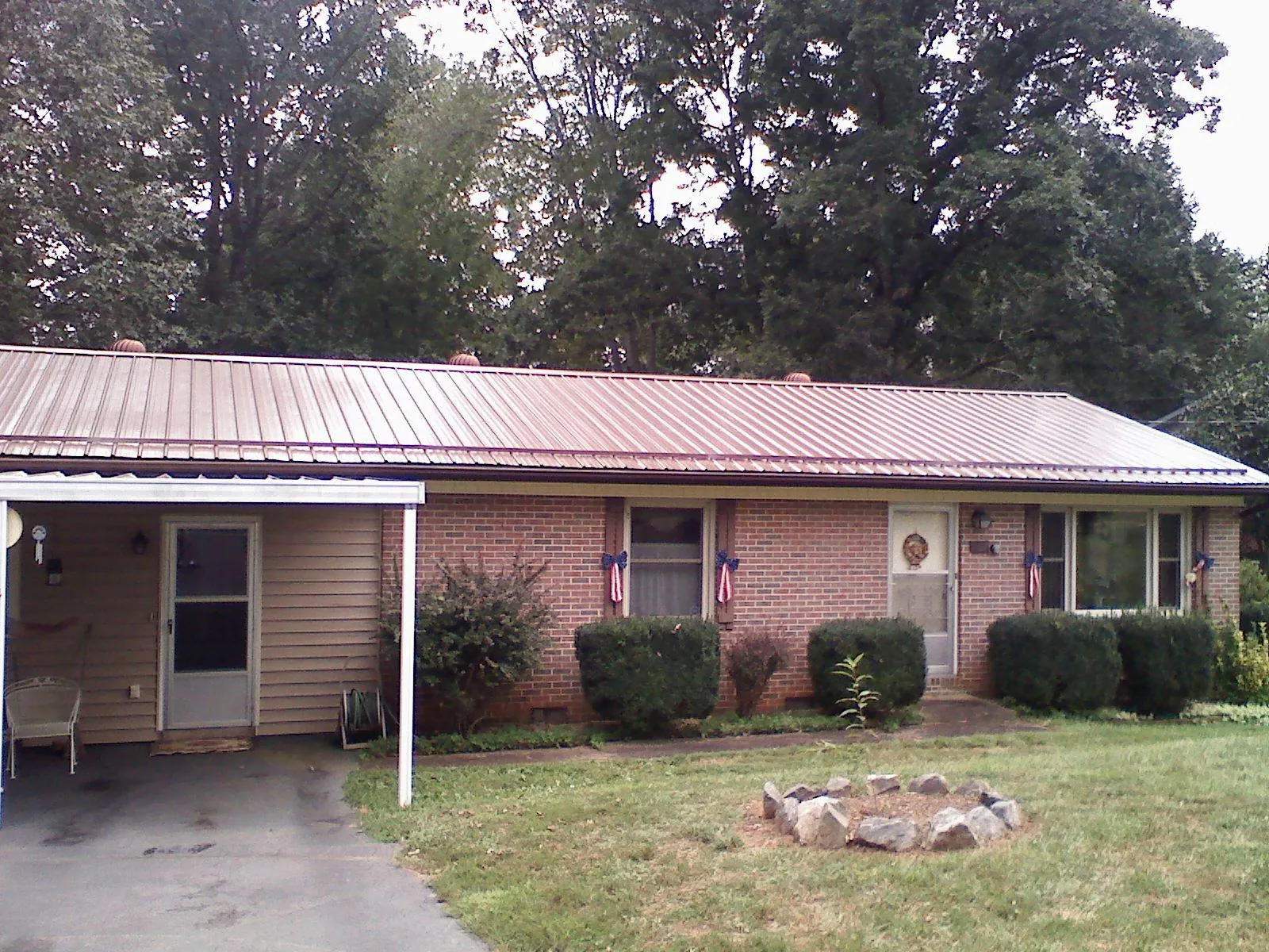 Bronze metal roof and carport on a brick ranch home — Roof Repair work by our crew in Mannsville